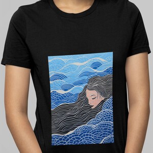 May include: A black t-shirt featuring a graphic print of a woman with long black hair submerged in blue and white waves.