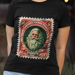 May include: Black t-shirt featuring a vintage-style Christmas stamp with Santa Claus. The stamp reads "Merry Christmas" and "North Pole".