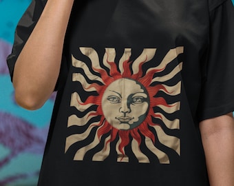 May include: Black t-shirt with a vintage sun and moon graphic. The sun has a face and is surrounded by red rays. The background is black and white stripes.
