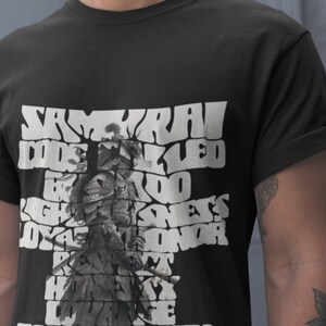 Peut inclure: T-shirt noir avec un graphique blanc d'un guerrier samouraï. Le graphique est composé des mots "Code Samouraï" et d'autres mots liés au code samouraï, tels que "honnêteté", "loyauté" et "courage".