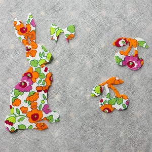 May include: A floral fabric bunny, two cherries, and a butterfly cut out from fabric. The fabric has a white background with orange, pink, and green floral patterns.