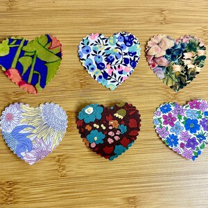Peut inclure: Six formes de cœur en tissu avec différents motifs floraux. Les cœurs sont de différentes couleurs, notamment le bleu, le vert, le rose, le jaune et le violet.