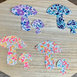 Puede incluir: Un conjunto de seis recortes de papel de setas con motivos florales. Las setas son de varios tamaños y colores, incluyendo azul, morado, amarillo y rosa.