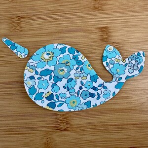 Peut inclure: Une découpe de narval florale bleue et blanche. Le narval est fait de tissu et a un motif floral.