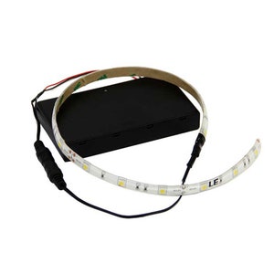 Op de afbeelding: Een witte LED-lichtstrip met een zwarte batterijpack en een zwarte draad. De lichtstrip is gebogen in een cirkelvorm. De batterijpack heeft een label met de tekst "LED".