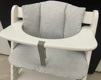 May include: White high chair with a gray fabric seat and a gray fabric back rest. The chair has a white tray.