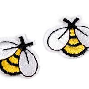 Könnte beinhalten: Zwei gestickte Bienenaufnäher. Jeder Aufnäher hat einen gelb-schwarz gestreiften Körper, weiße Flügel und eine schwarze Umrandung. Die Aufnäher befinden sich auf weißem Hintergrund.