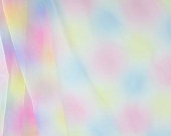 May include: A soft, flowing fabric with a pastel color palette. The material features a blend of pink, yellow, blue, and white hues, creating a dreamy, ethereal effect. The fabric's texture appears delicate and lightweight, with subtle folds and movement.