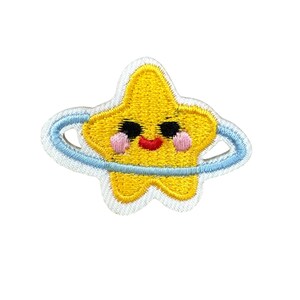 Könnte beinhalten: Gestickter Aufnäher mit einem lächelnden gelben Stern mit einem hellblauen Ring. Der Stern hat schwarze Augen, einen roten Mund und rosa Wangen. Der Aufnäher ist weiß umrandet.