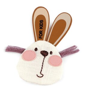 Könnte beinhalten: Ein weißer Stoffhase mit braunen Filzohren und rosa Filzbacken. Die Ohren sind mit dem Text "FOR KIDS" bedruckt.