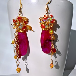May include: A pair of dangle earrings with pink agate stones, gold wire, and a mix of red, orange, and white beads.