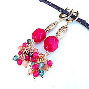 May include: Gold-coloured drop earrings with faceted fuchsia stones and clusters of small, multi-coloured beads. The earrings have intricate filigree details and are suspended from a small hoop with clear stones.