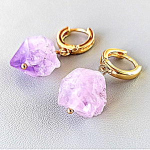 May include: A pair of gold hoop earrings with a dangling amethyst crystal. The crystals are raw and have a natural, irregular shape.