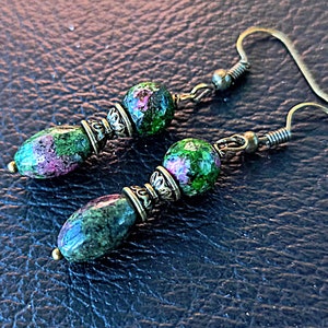 May include: A pair of earrings with green and pink gemstone beads and antique gold accents.