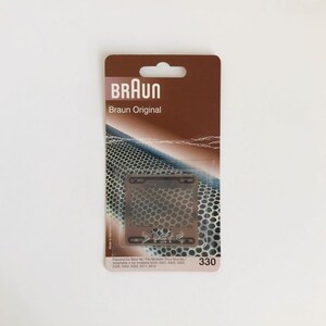 Puede incluir: Una pieza de repuesto de lámina de afeitadora Braun plateada en un paquete marrón y blanco. El paquete dice "Braun Original" y enumera los números de modelo compatibles. La lámina tiene el texto "PET" impreso en ella.