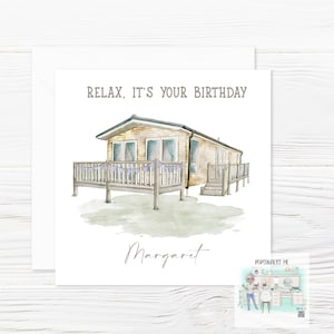 May include: A watercolour illustration of a brown and white mobile home with a wooden deck and purple bunting. The text "Relax, it's your birthday" is above the image and the name "Margaret" is below the image.