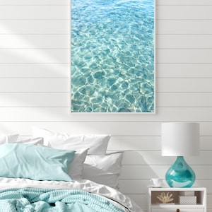 May include: A framed photograph of a turquoise blue ocean with ripples and sunlight reflecting on the surface.