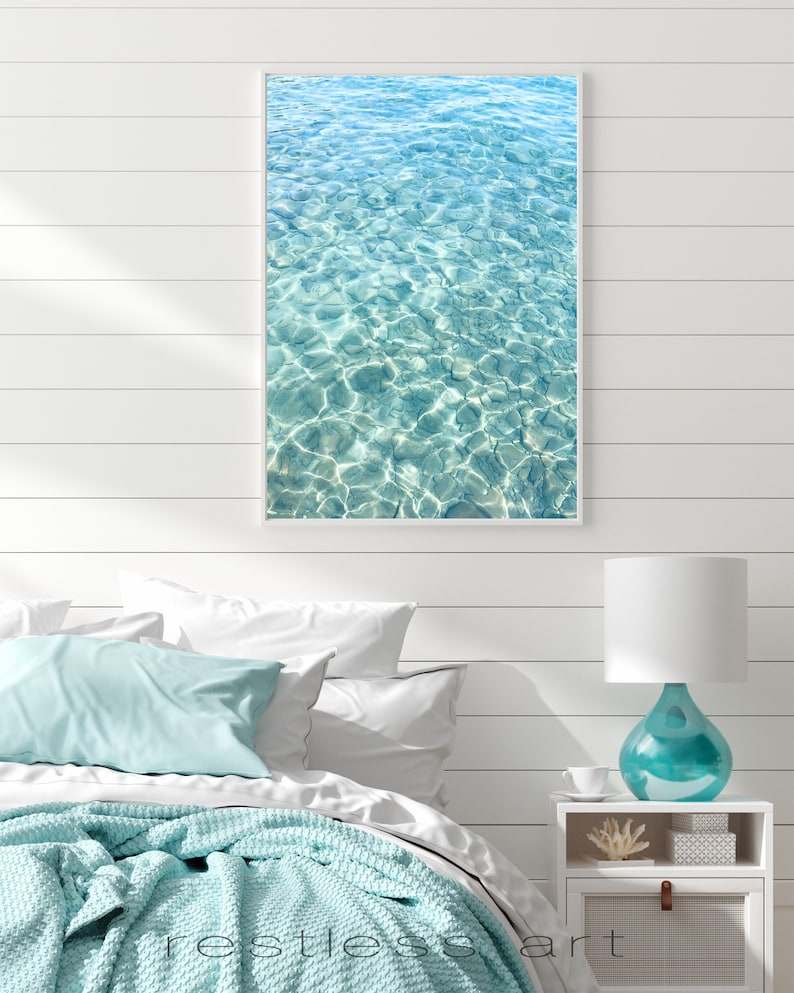 May include: A framed photograph of a turquoise blue ocean with ripples and sunlight reflecting on the surface.