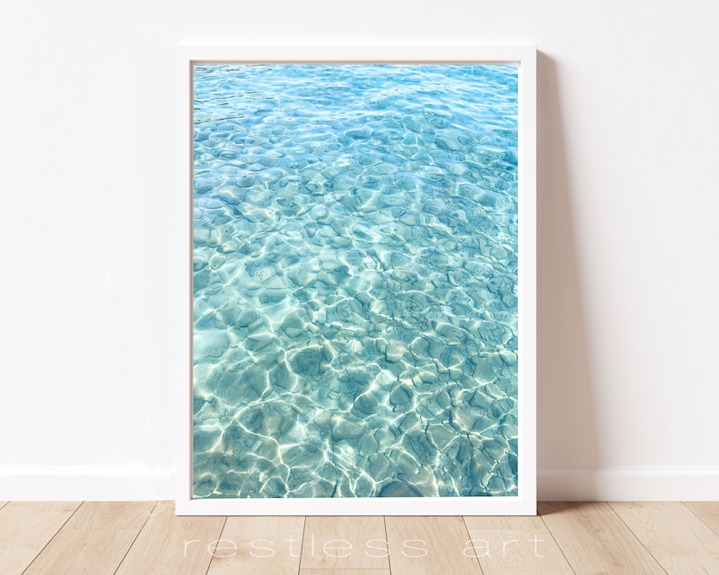 May include: A close-up photograph of clear, turquoise water with ripples and light reflecting on the surface.