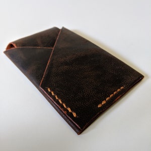 May include: A dark brown leather wallet with a folded design and contrasting light brown stitching.