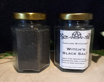 Puede incluir: Dos frascos de vidrio llenos de sal negra. Los frascos tienen tapas doradas y etiquetas que dicen "Familiars Witchcraft Witch's Black Salt Used for protection, banishing and cleansing spells and rituals. Not suitable for consumption."
