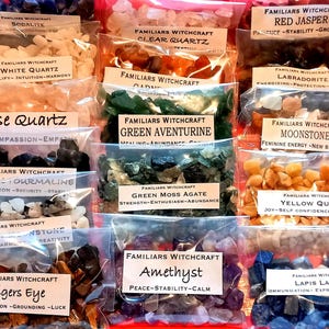 May include: A selection of small plastic bags filled with gemstones, each labelled with the stone's name and properties. Stones include Sodalite, Clear Quartz, Red Jasper, White Quartz, Rose Quartz, Black Tourmaline, Green Aventurine, Green Moss Agate, Moonstone, Yellow Quartz, Rainbow Moonstone, Tigers Eye, Amethyst, and Lapis Lazuli.