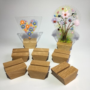 May include: Eight wooden display stands with a slot for holding a piece of art. Two pieces of glass art are shown on the stands, one with a heart design and the other with a floral design.