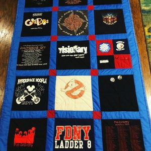 May include: A blue and red patchwork quilt made from t-shirts. The quilt features various band logos and designs, including "Gods & Dolls", "Nothing On", "Visionary", "Hyperspace Hoopla", "FDNY Ladder 8", and "The Bravery".