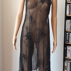 May include: A black sheer dress with floral embroidery. The dress has a halter neckline and a loose fit.