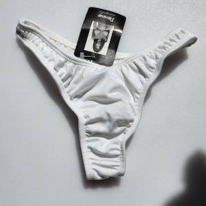 May include: White silky thong underwear with a small black tag that says "Dreamwear" on it.