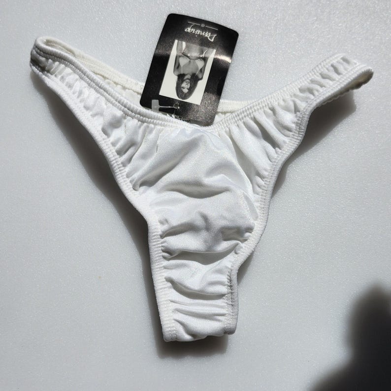 May include: White silky thong underwear with a small black tag that says "Dreamwear" on it.