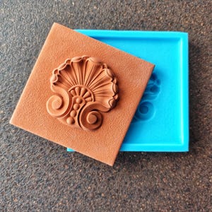 Peut inclure: Un moule en silicone brun avec un motif floral détaillé. Le moule est ouvert et montre le motif dans le moule.