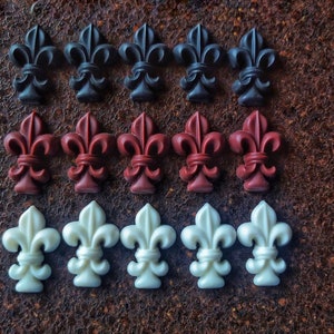 Puede incluir: Tres filas de flores de lis decorativas, cada fila de un color diferente: negro, burdeos y blanco.