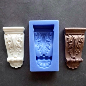 Può includere: Tre stampi in silicone per realizzare mensole decorative. Gli stampi sono blu, bianchi e marroni. Le mensole hanno un design a foglie.