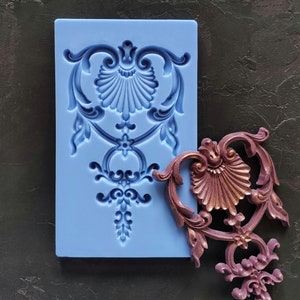 以下が含まれることがあります： 詳細な装飾的なデザインが施された青いシリコンモールドと、デザインに合わせた紫色のレジンキャスト