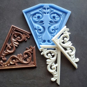 May include: Three decorative corner mouldings, one in blue silicone, one in white plastic, and one in brown metal. The mouldings are all in the shape of a corner with intricate floral designs.