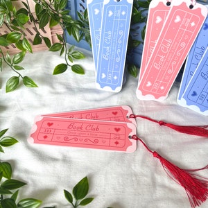 May include: Four pink and blue bookmark tickets with the text "Book Club" and "Once upon a time" with a star and heart design. The bookmarks have red tassels.