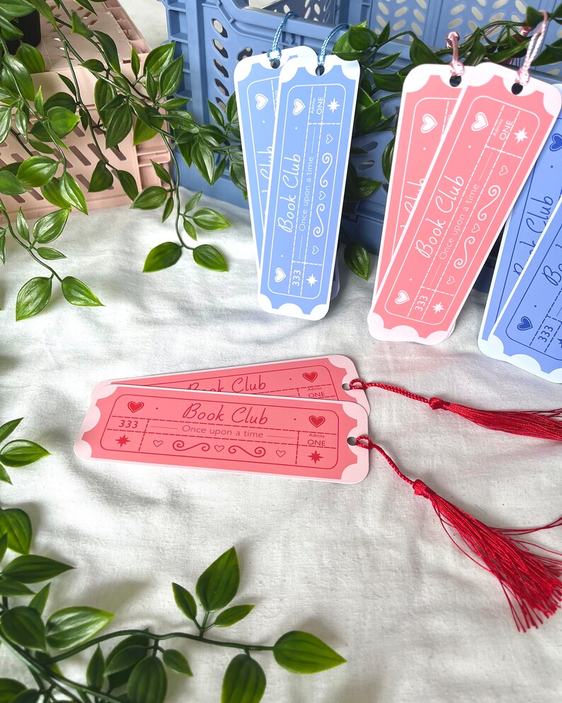 May include: Four pink and blue bookmark tickets with the text "Book Club" and "Once upon a time" with a star and heart design. The bookmarks have red tassels.