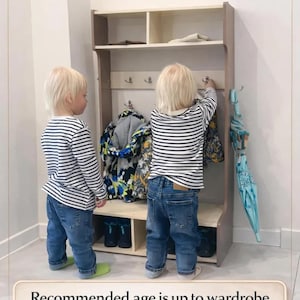 May include: A light-colored wooden entryway storage unit featuring an upper shelf, a middle section with metal hooks for hanging items, and a lower shelf with two compartments for shoes. The unit includes text reading Ideal for Two Children.