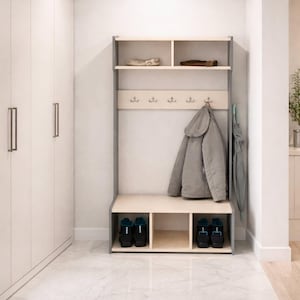 May include: A light wood and grey hall tree featuring an upper shelf with two compartments, a middle section with five metal hooks for hanging items, and a lower bench with three open storage cubbies for shoes, positioned against a white wall.