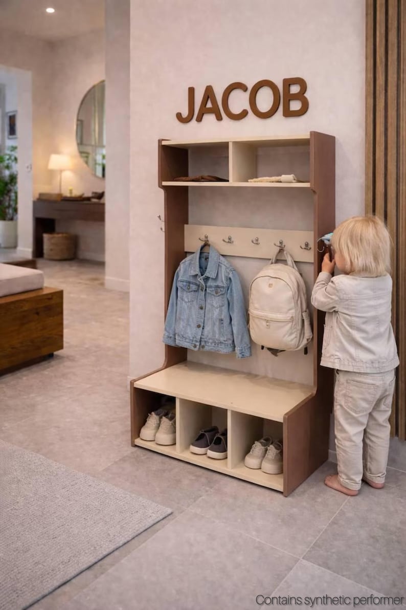 May include: A wooden entryway storage unit with a top shelf, a middle section featuring four metal hooks, and a bottom bench with three open cubbies for shoes. The name JACOB is mounted in large brown letters on the wall above the storage unit.