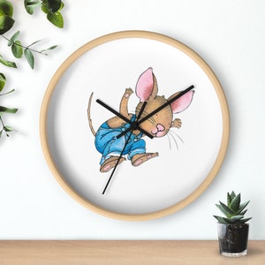 May include: A round wooden wall clock with a white face and black hands. The clock features a cartoon illustration of a brown mouse wearing blue overalls and a pink nose. The mouse is jumping and has a long tail.