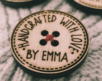 May include: A wooden button with a red thread sewn through the holes. The button is engraved with the text "HANDCRAFTED WITH LOVE BY EMMA".