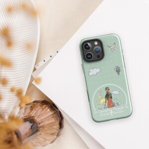 Puede incluir: Una funda de teléfono verde con un contorno blanco de una mujer sosteniendo una flor y una paloma. El texto en la funda dice "St. Dymphna Pray for Us The Lily of Binche Patroness of Martyrs".