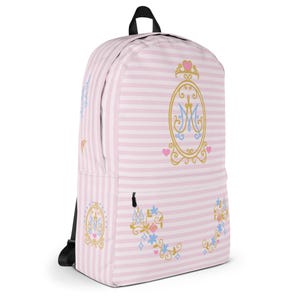 May include: Pink and white striped backpack with a black handle and straps. The backpack features gold and blue decorative emblems with the letter "M" and floral accents. Small pink hearts and blue floral designs are also present.