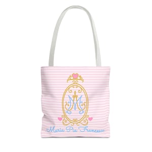 Può includere: Una borsa tote a righe rosa e bianche con manico bianco. La borsa presenta un design ovale dorato con le lettere "M" e una corona, e le parole "Maria Pia Francesca" in blu.