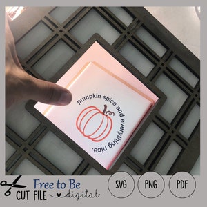 Può includere: Un file di taglio digitale che presenta una zucca con il testo "pumpkin spice and everything nice". Il design è mostrato in una cornice di legno.