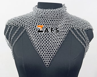 May include: Silver chainmail collar and shoulder piece with a triangular shape. The chainmail is made of small, interlocking metal rings. The piece is displayed on a black mannequin.