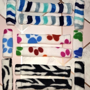 May include: A set of 10 colourful fleece dog chew toys. The toys are in various patterns, including stripes, paw prints, and zebra print. The toys are all about 15 cm long.