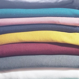 May include: A stack of folded fabric in various colors, including teal, pink, black, yellow, burgundy, gray, and white.